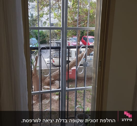 חלון זכוכית עם סורגים מתכתיים ועץ ברקע